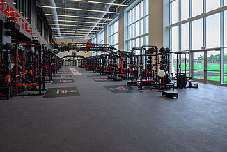 View of entrance of Texas Tech Football weight room, showcasing the number of weight training racks and REGUPOL crash platforms.