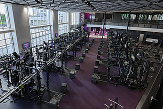 Full view of the TCU football performance center, with a view of the football stadium in the background. The facility allows athletes to improve their performance through a variety of equipment. 